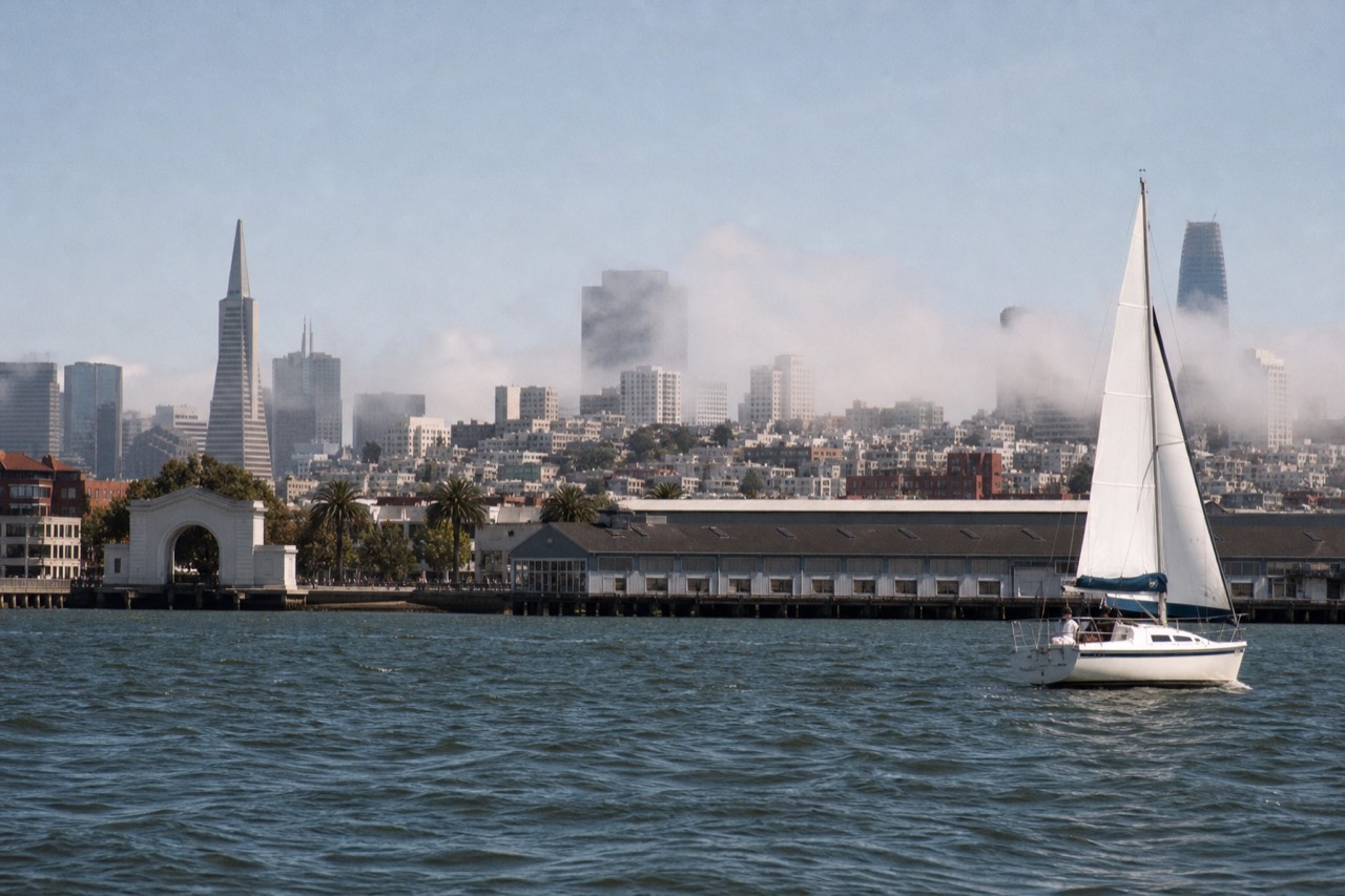 The hillside town of Sausalito stacked above a marina of white yachts, wooded ridges rising behind and boats swinging at their moorings in still afternoon light.
